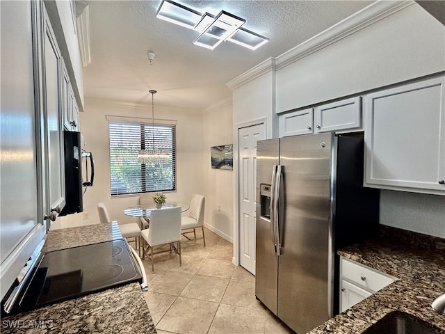 kitchen with stainless steel refrigerator with ice dispenser, hanging light fixtures, light tile patterned floors, crown molding, and dark stone countertops