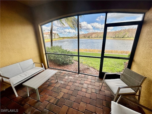 sunroom featuring a water view