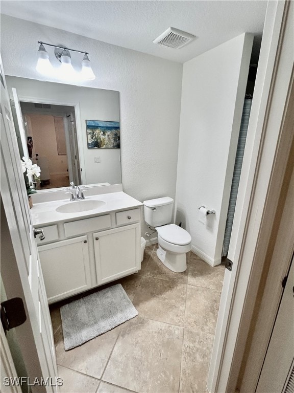 bathroom with toilet, vanity, and tile patterned flooring