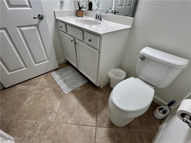 bathroom with toilet, vanity, and tile patterned floors