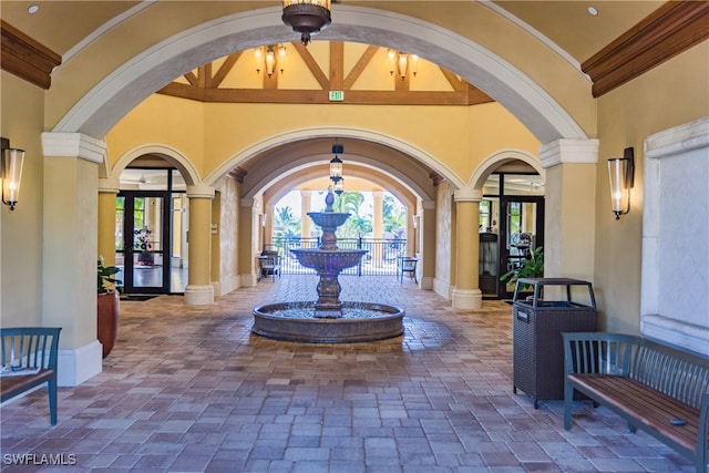 foyer with ornamental molding, beam ceiling, high vaulted ceiling, decorative columns, and french doors