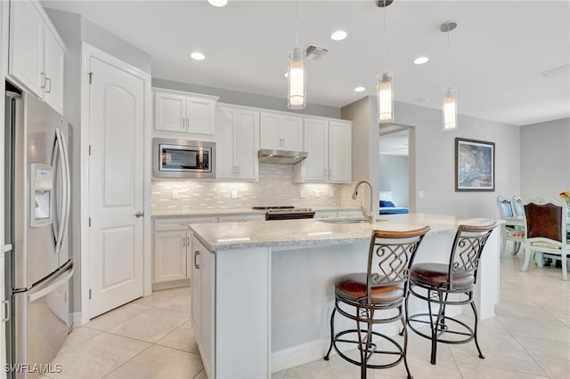 kitchen featuring stainless steel appliances, white cabinets, a kitchen island with sink, and decorative light fixtures