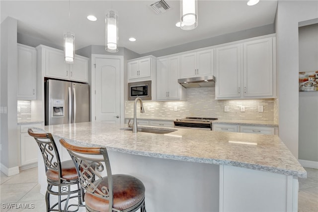 kitchen featuring white cabinetry, sink, appliances with stainless steel finishes, light tile patterned floors, and an island with sink