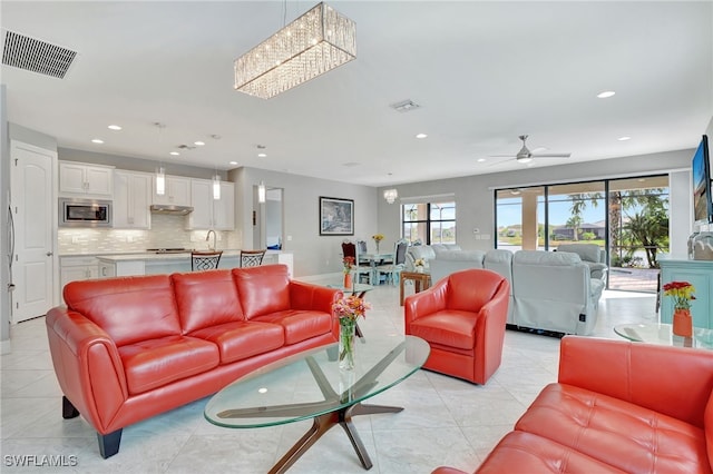 living room featuring ceiling fan with notable chandelier and light tile patterned floors