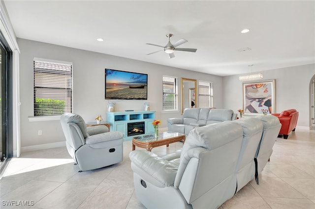 tiled living room with ceiling fan with notable chandelier