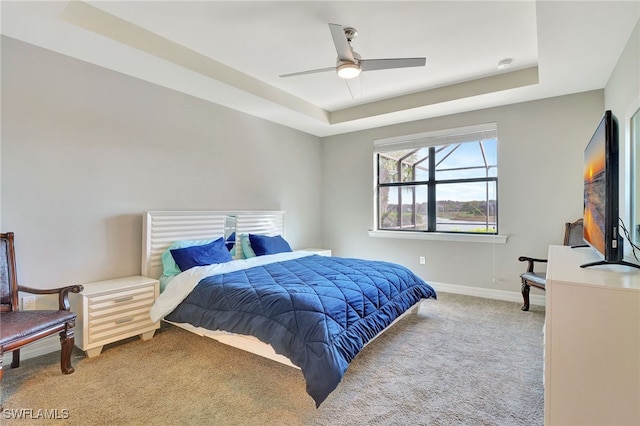 carpeted bedroom featuring ceiling fan and a tray ceiling