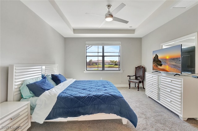 bedroom featuring ceiling fan, light carpet, and a tray ceiling