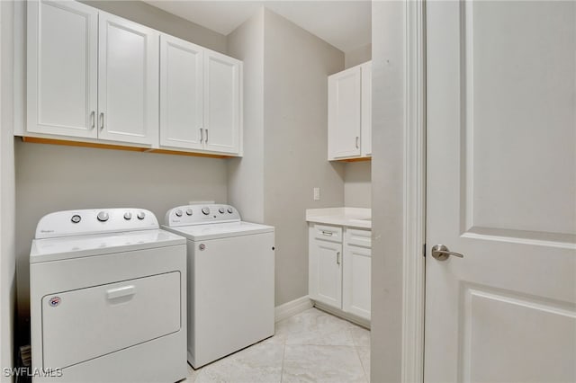 clothes washing area with cabinets and separate washer and dryer