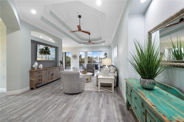 interior space with ornamental molding, light hardwood / wood-style floors, ceiling fan, and a raised ceiling