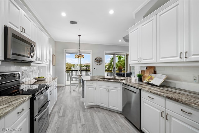 kitchen with stainless steel appliances, white cabinets, decorative backsplash, sink, and light stone countertops