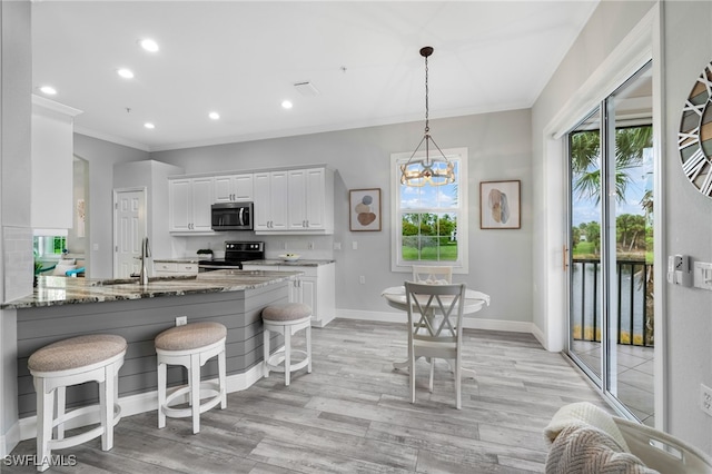 kitchen featuring light hardwood / wood-style floors, white cabinetry, dark stone countertops, a notable chandelier, and black range with electric cooktop