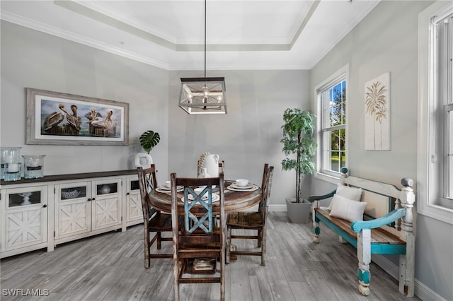 dining space featuring hardwood / wood-style flooring, a notable chandelier, a tray ceiling, and ornamental molding