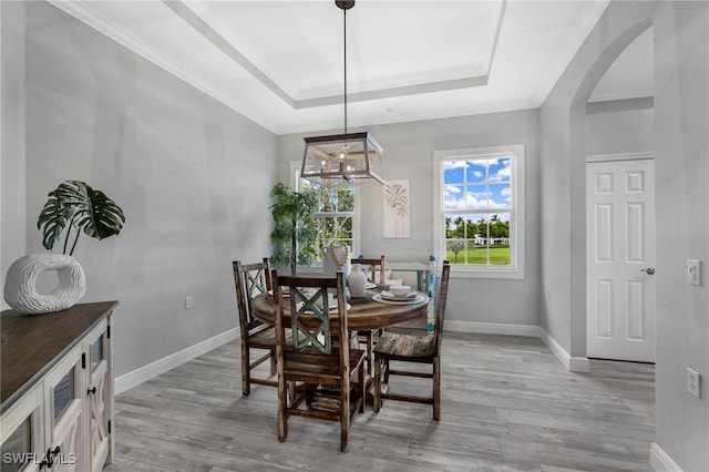 dining area featuring light wood-type flooring, crown molding, and a tray ceiling