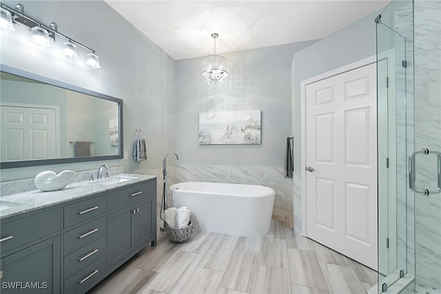 bathroom featuring a chandelier, vanity, plus walk in shower, and tile walls