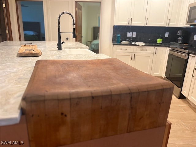 kitchen with sink, appliances with stainless steel finishes, decorative backsplash, and a center island with sink