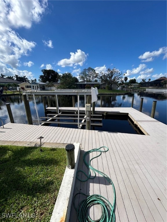 view of dock with a water view and a yard