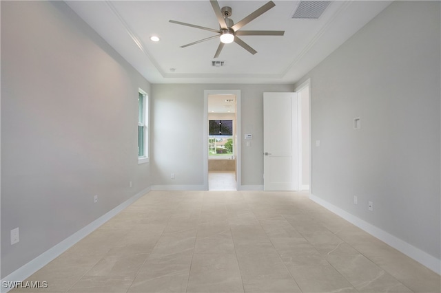 spare room with a tray ceiling, light tile patterned floors, and ceiling fan