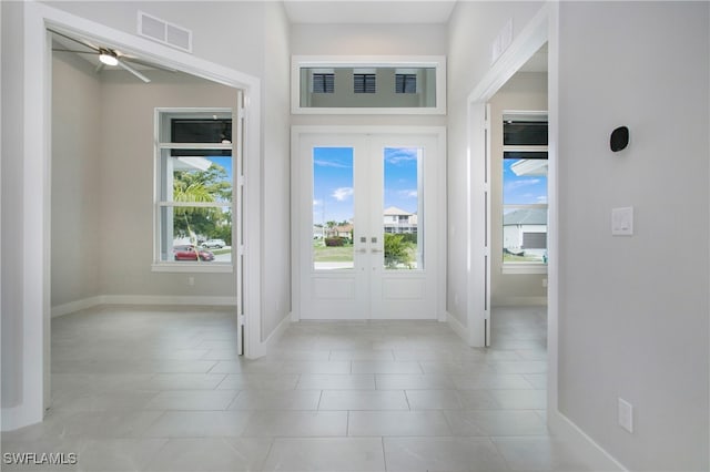 foyer entrance with ceiling fan, light tile patterned floors, and french doors