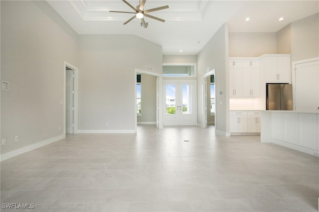 unfurnished living room featuring a towering ceiling, ceiling fan, light tile patterned floors, and ornamental molding