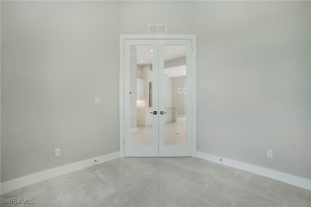 unfurnished bedroom featuring light tile patterned floors, french doors, and a notable chandelier