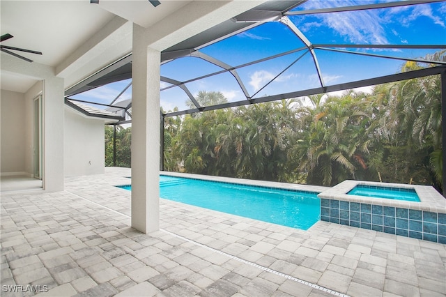 view of swimming pool featuring glass enclosure, ceiling fan, an in ground hot tub, and a patio area