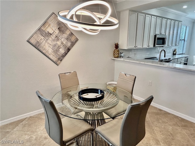 dining area featuring light tile patterned floors, sink, crown molding, and an inviting chandelier