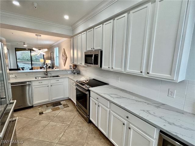 kitchen with hanging light fixtures, sink, crown molding, white cabinetry, and appliances with stainless steel finishes