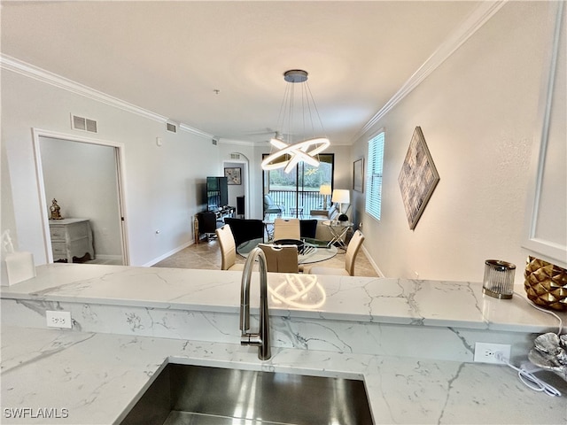 interior details with sink, light stone counters, a chandelier, crown molding, and pendant lighting