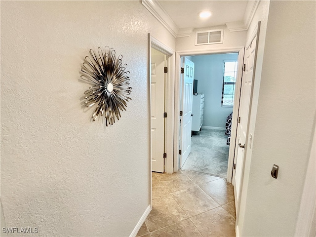 hallway featuring light tile patterned floors and crown molding