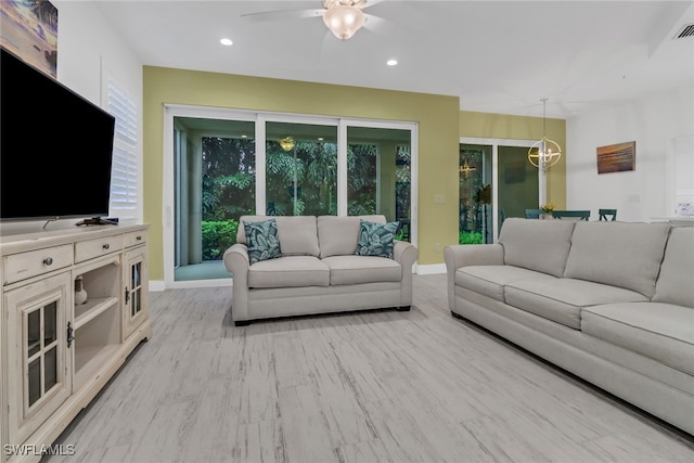 living room featuring light hardwood / wood-style floors and ceiling fan with notable chandelier