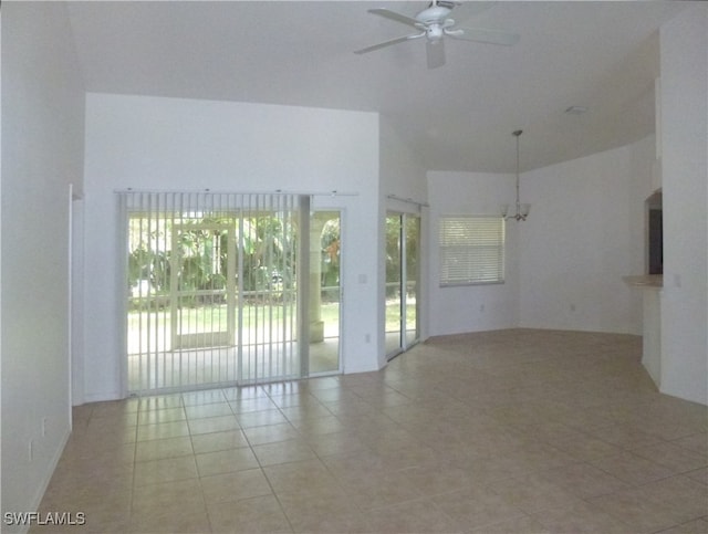 tiled empty room featuring a wealth of natural light and ceiling fan with notable chandelier