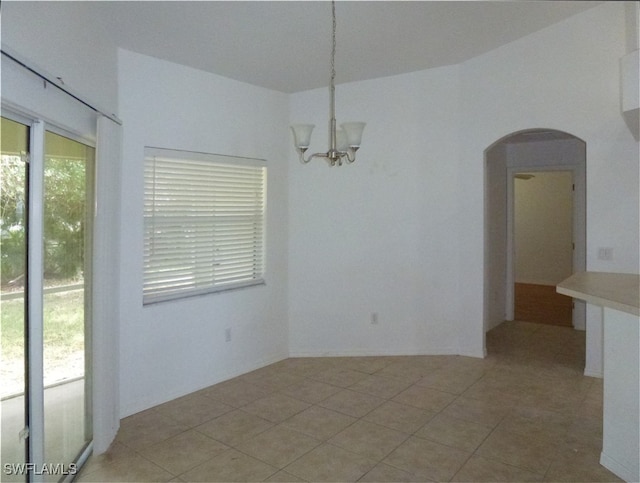 tiled spare room with an inviting chandelier