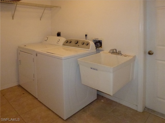 laundry room with washing machine and clothes dryer, light tile patterned floors, and sink