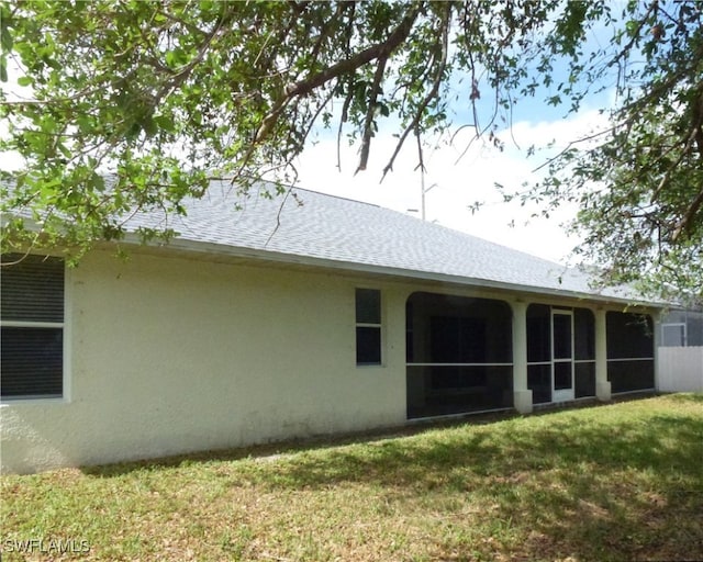 rear view of property with a sunroom and a lawn