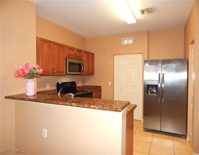 kitchen featuring stainless steel appliances, dark stone countertops, light tile patterned floors, and kitchen peninsula