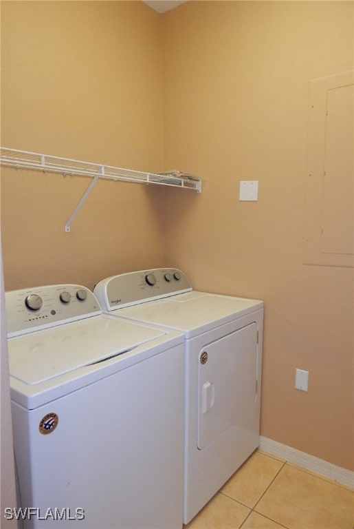 laundry area with electric panel, washing machine and dryer, and light tile patterned flooring