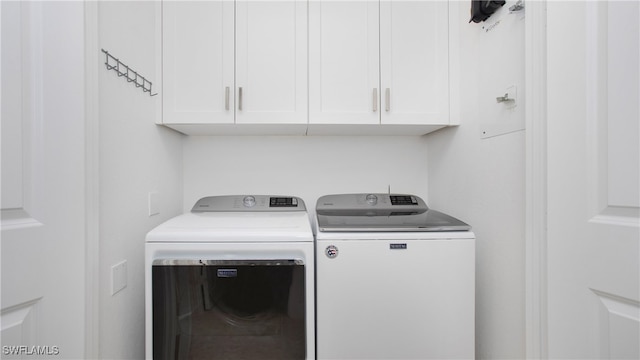 clothes washing area featuring cabinets and separate washer and dryer