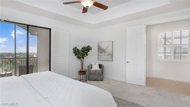 carpeted bedroom featuring ceiling fan, access to exterior, multiple windows, and a tray ceiling