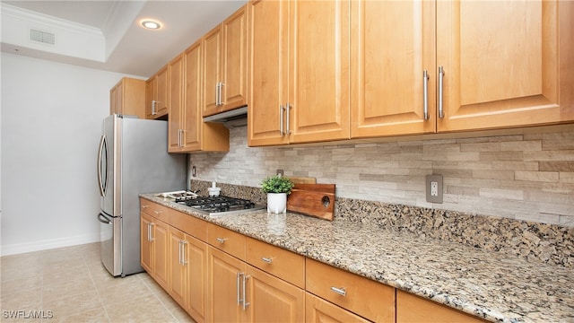 kitchen with crown molding, backsplash, appliances with stainless steel finishes, light tile patterned floors, and light stone countertops