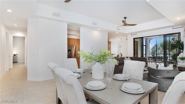 dining area with ornamental molding, a tray ceiling, and light tile patterned flooring