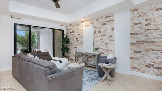 tiled living room featuring ceiling fan, a tray ceiling, and ornamental molding