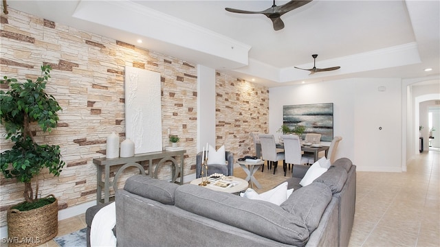 tiled living room with a tray ceiling, ceiling fan, and crown molding