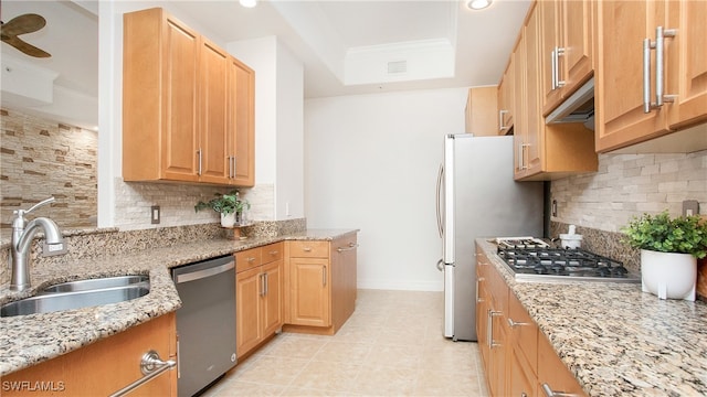 kitchen with stainless steel appliances, sink, light stone counters, and backsplash