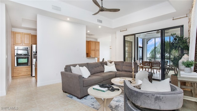 tiled living room with ornamental molding, ceiling fan, and a tray ceiling