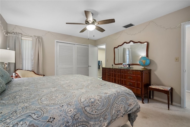 bedroom with light colored carpet, ceiling fan, and a closet