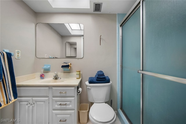 bathroom featuring toilet, vanity, and a shower with door