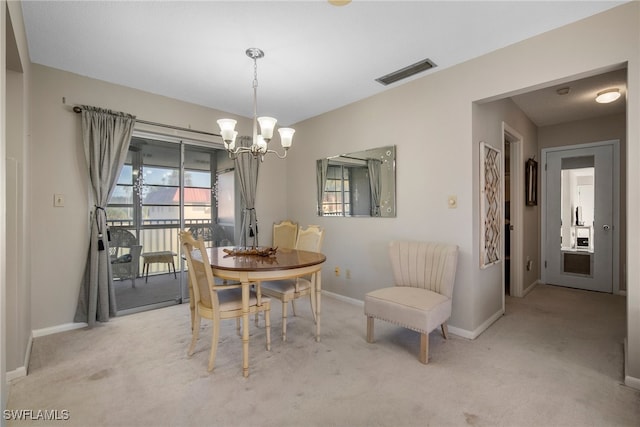 dining room featuring light carpet and a chandelier