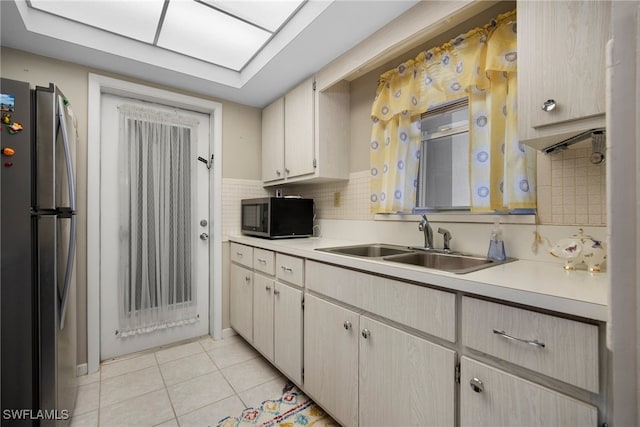 kitchen featuring stainless steel appliances, light tile patterned flooring, sink, and backsplash