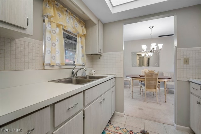 kitchen with a chandelier, light tile patterned floors, pendant lighting, sink, and a skylight