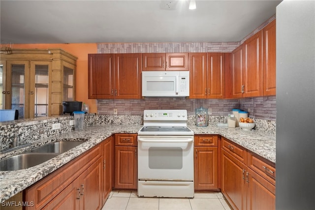 kitchen featuring light stone counters, light tile patterned flooring, decorative backsplash, sink, and white appliances